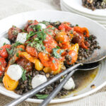 An image of black lentils with tomatoes in a bowl with mozzarella