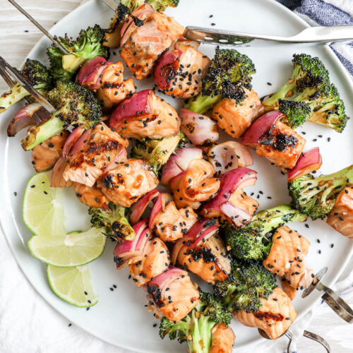 An overhead image of salmon kabobs on a white plate