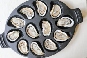 An overhead image of shucked oysters in a grill pan