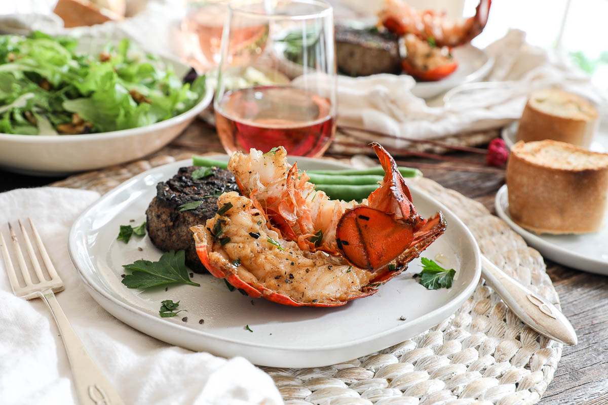 An image of a surf and turf dinner on a table with rose wine.