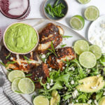 An overhead image of blackened cod loins with a vibrant green salad