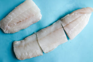 An image of cod on a blue cutting board. 