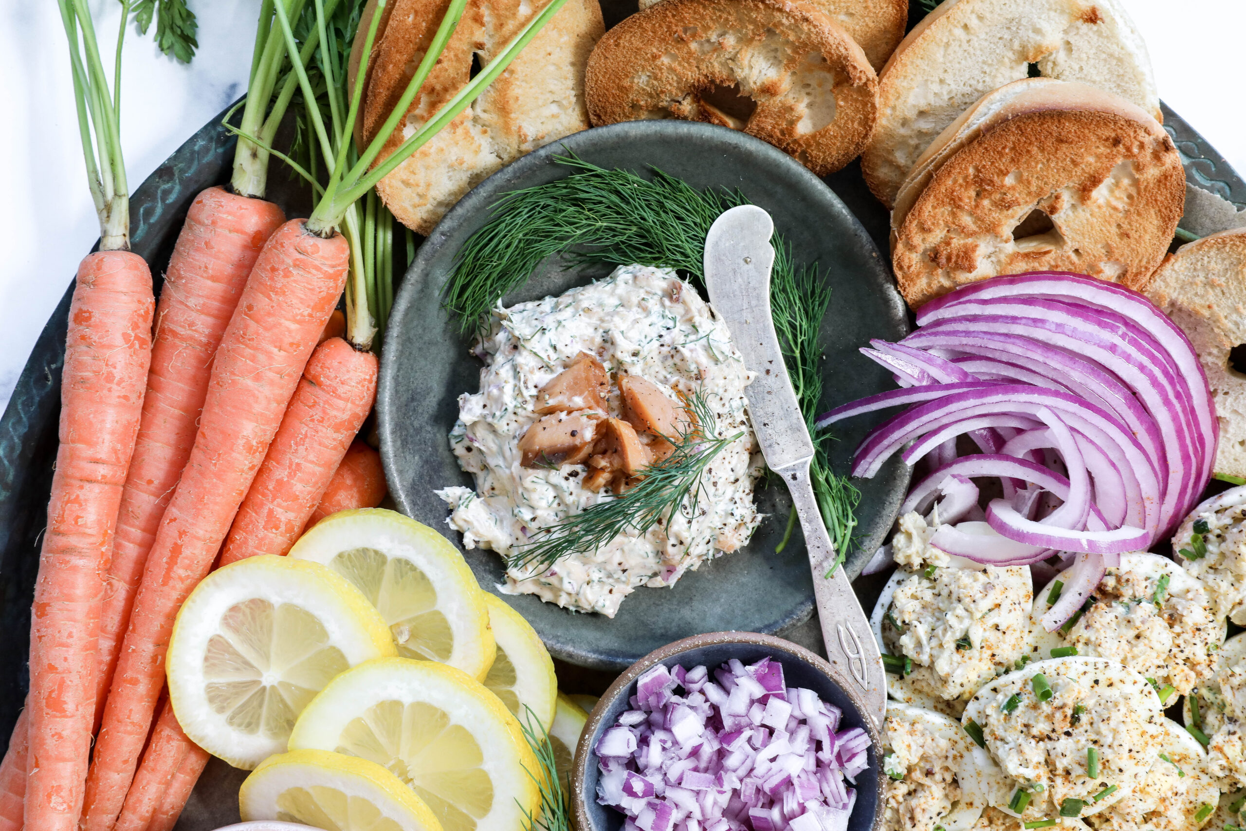 A closeup image of smoked salmon dip on a large spring seacuterie seafood platter.