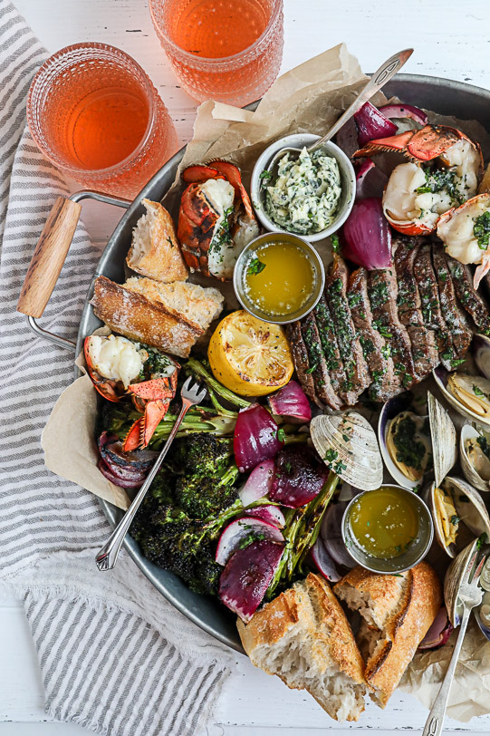 A surf and turf platter on a silver serving board.