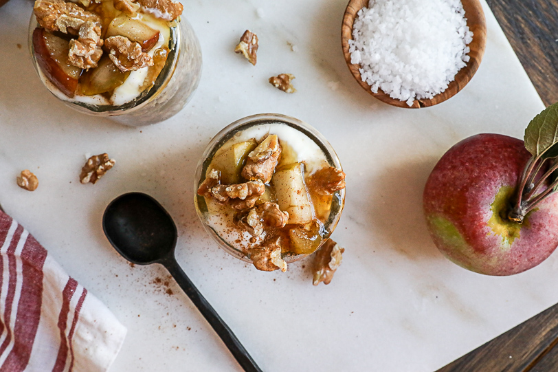 An overhead image of jars of overnight oats with apples and walnuts and honey on top.