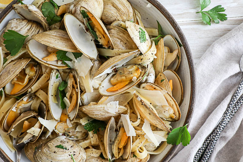 An overimage close up image of clams and pasta in a bowl. 