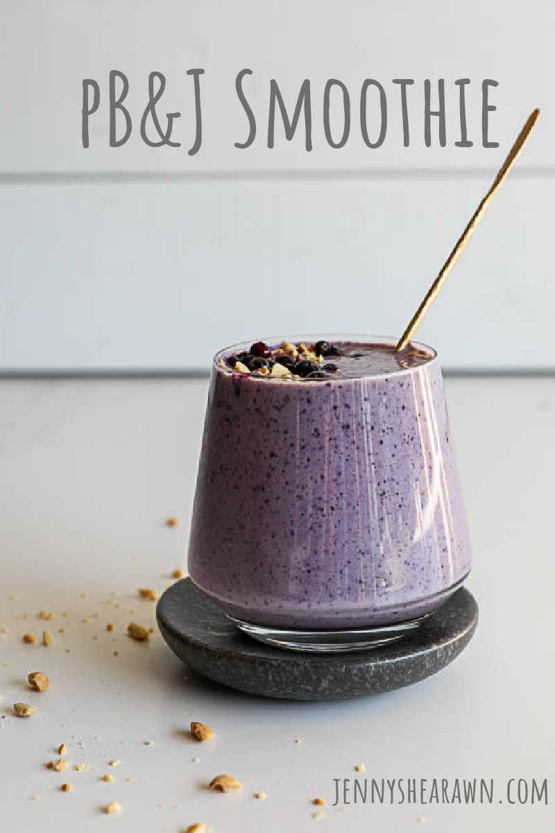 An image of a peanut butter and jelly wild blueberry smoothie on a white counter with a white background