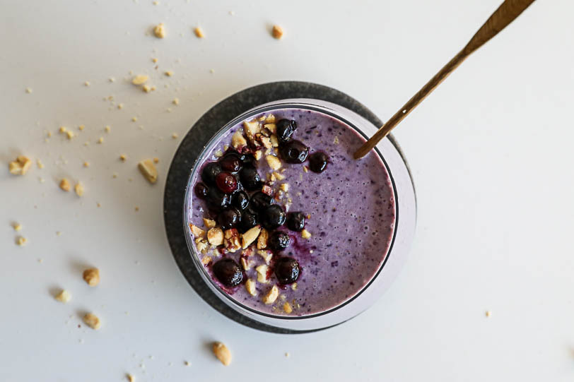 An overhead image of a wild blueberry smoothie with blueberries and peanuts on the top
