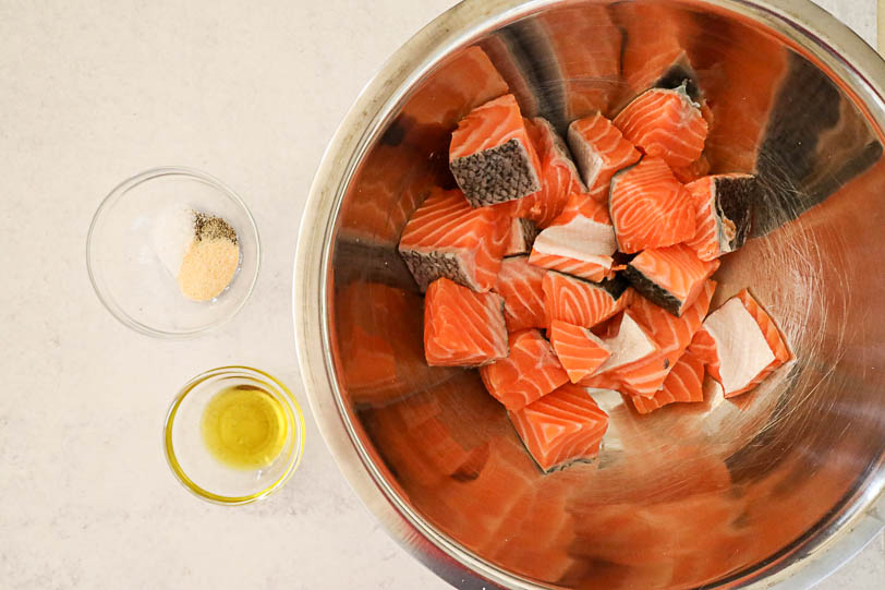 Ingredients for these air fryer salmon bites - salmon, olive oil, garlic powder, salt and pepper in bowls.