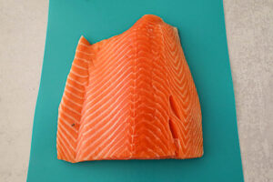 An image of a raw salmon fillet on a blue cutting board. 