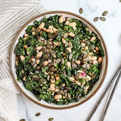 An overhead image of a kale and white bean salad with pumpkin seeds.