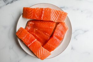 An image of salmon fillets on a white plate. 