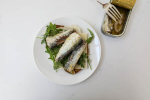 An overhead image of sardines on arugula and whole wheat bread.