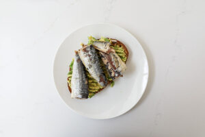 An overhead image of toast with avocado and sardines