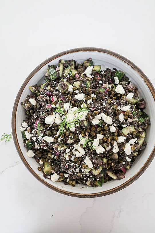 An overhead image of a lentil salad on a white countertop. 