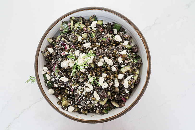 An overhead image of a black lentil salad with feta cheese.