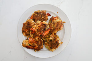 An overhead image of cooked lobster cakes on a white plate.