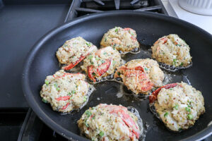 An image of lobster cakes pan frying. 