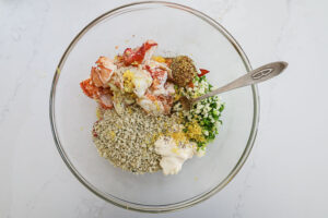 An overhead image of ingredients for lobster cakes in a bowl.