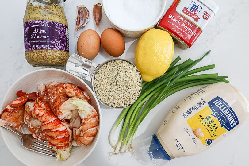 An overhead image of ingredients for lobster cakes on a white counter. 