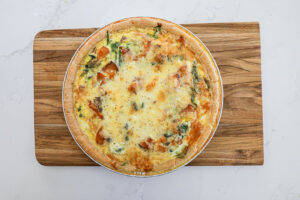 An overhead image of a whole salmon spinach quiche.