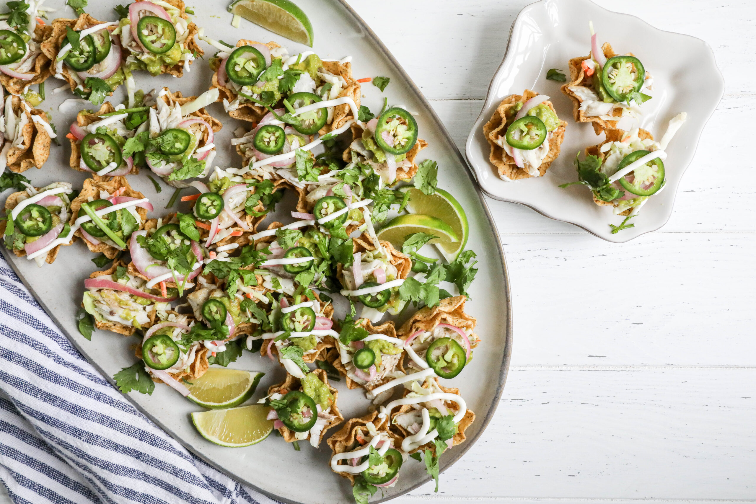 An image of a large platter of bluefish taco bites with lime wedges.