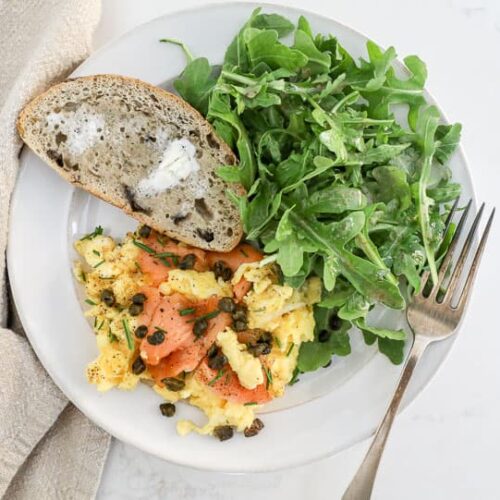 An overhead image of smoked salmon eggs with toast and an arugula salad.