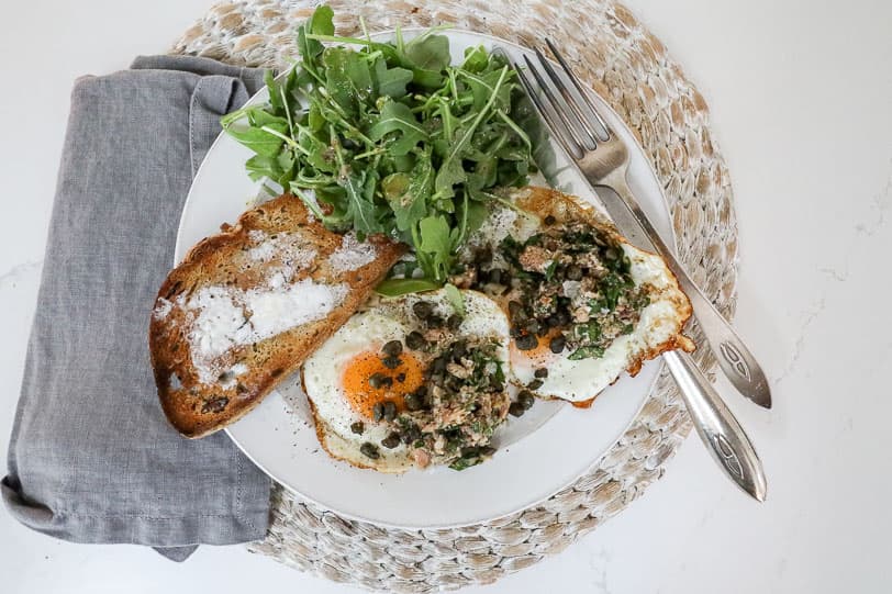 An overhead image of sardine eggs with arugula and buttered toast. 