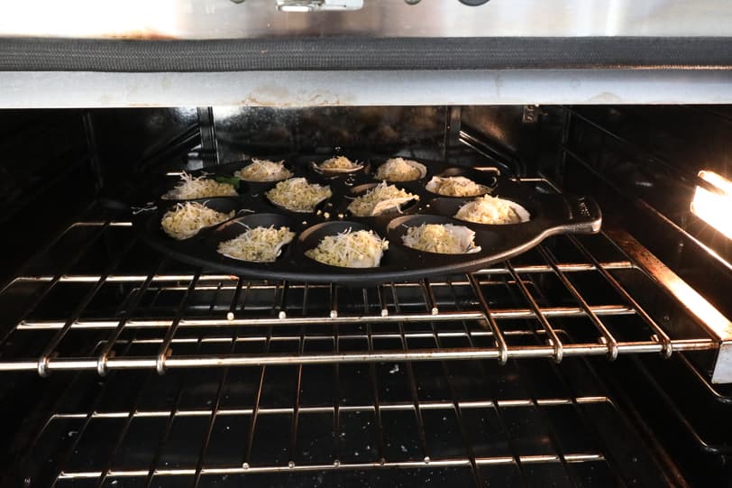 An image of oysters going into the oven in a cast iron pan. 