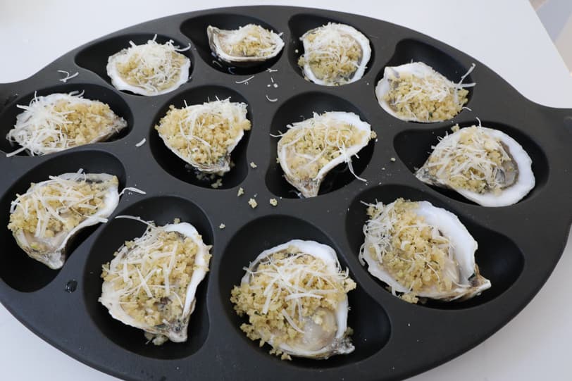 An image of shucked oysters with breadcrumbs and cheese. 