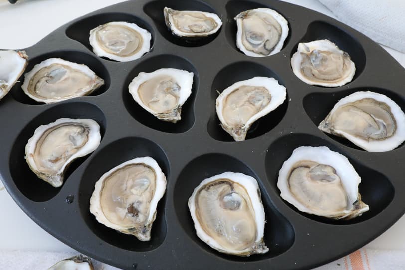 An image of freshly shucked oysters in an oyster pan. 