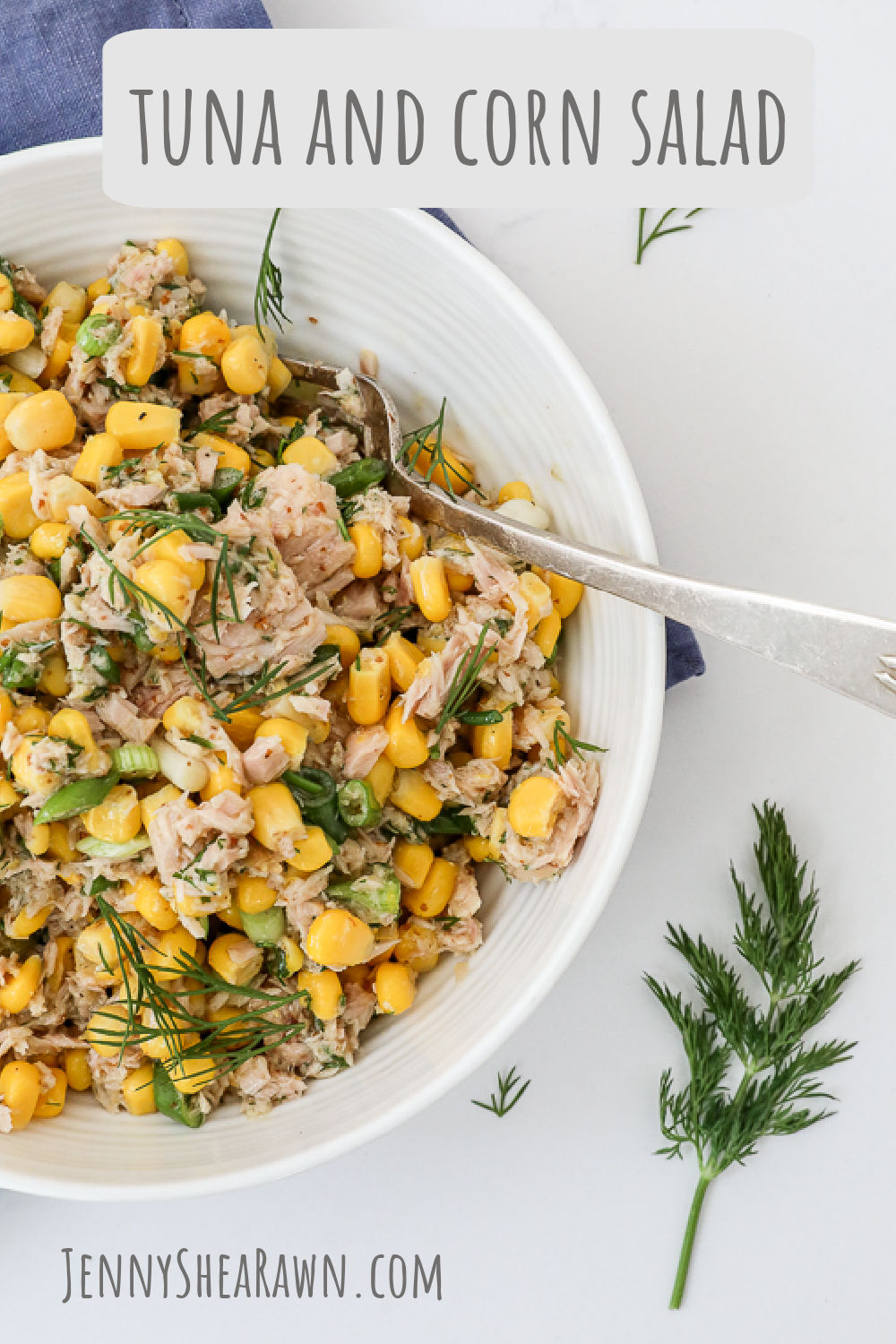 An image of a tuna and corn salad recipe served in a white bowl on a white counter. 