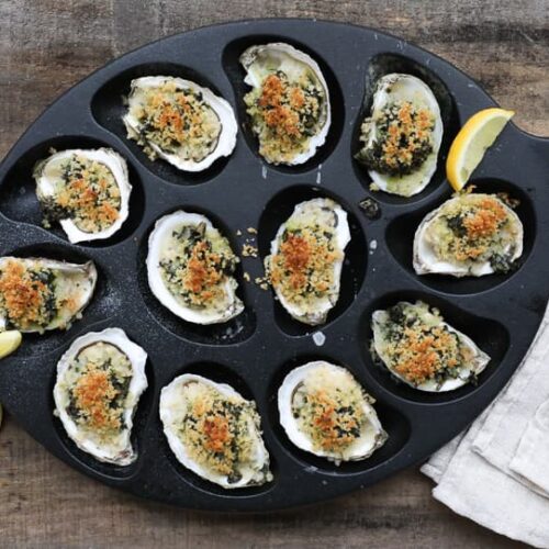 An image of baked Oysters Rockefeller in an oyster pan.