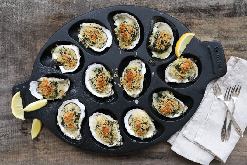 An image of baked Oysters Rockefeller in an oyster pan.