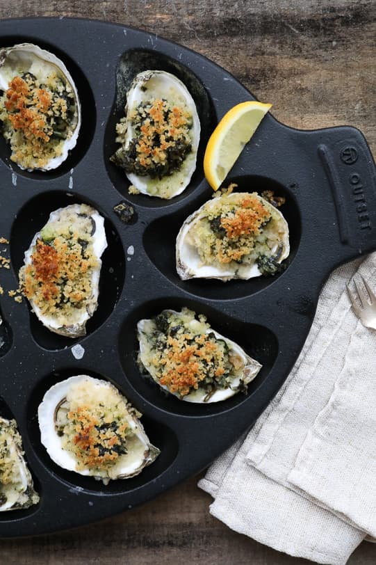 An overhead image of Oysters Rockefeller on an oyster roasting pan. 