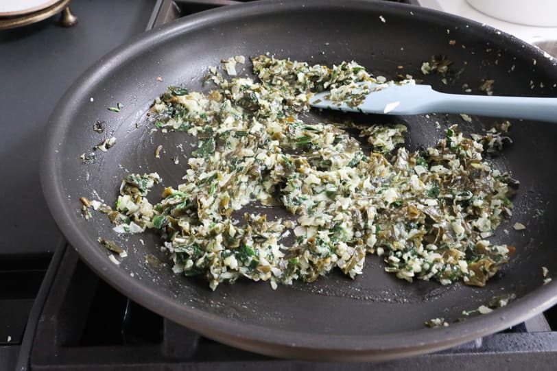 An image of shallot, spinach, garlic and kelp in a skillet.