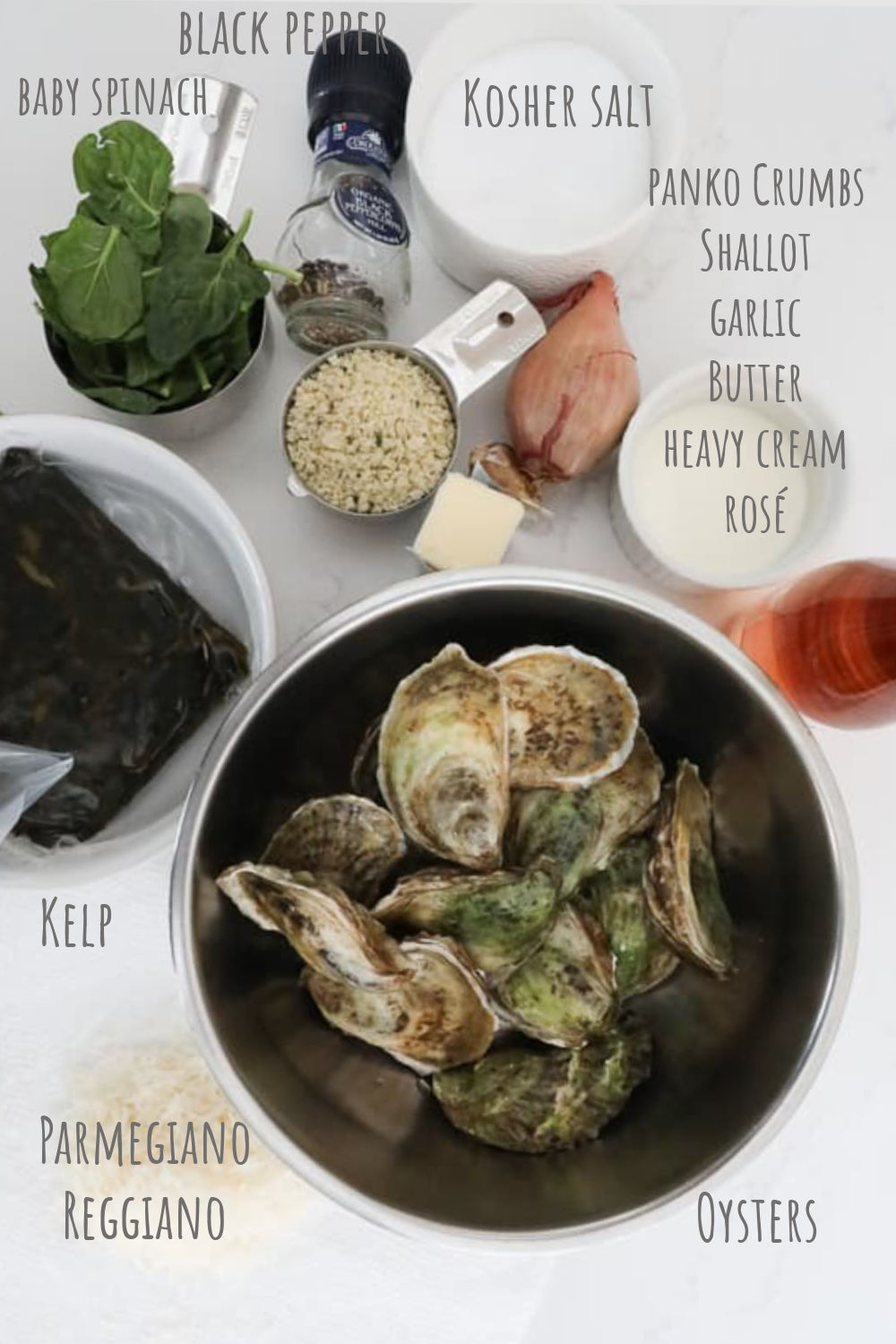 An image of all the ingredients needed to make Oysters Rockefeller, including: oysters, kelp, parmesan, panko crumbs, spinach, butter, cream, garlic, shallot and wine. 