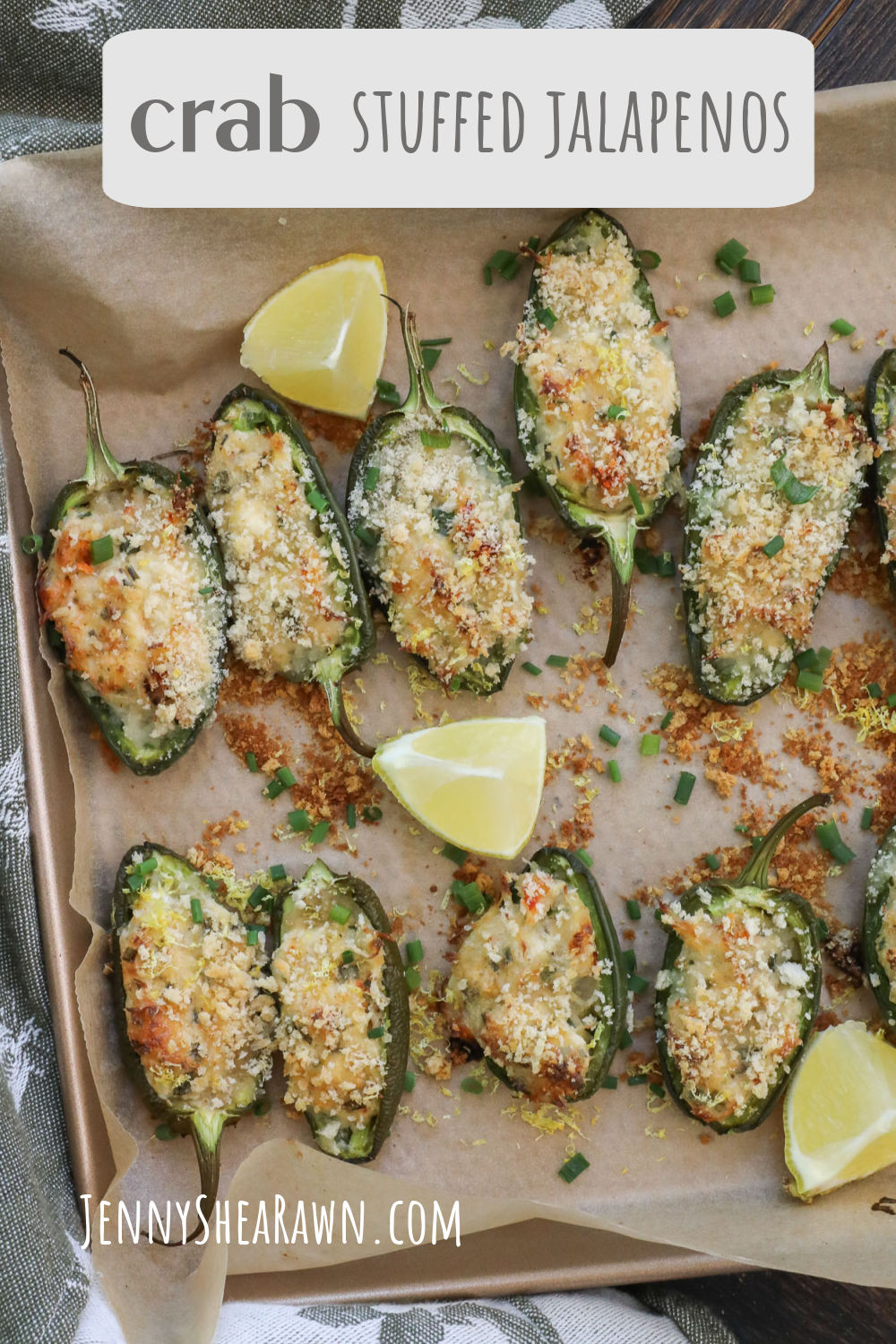 Crab stuffed jalapenos on a baking sheet lined with parchment paper with lemon wedges scattered around. 