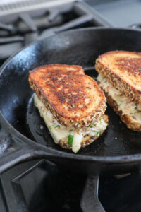 An image of 2 crab grilled cheeses in a cast-iron skillet. 