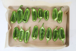 Hollowed jalapenos on a baking sheet ready to be stuffed. 