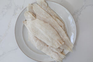 An image of breaded sole fillets on a white plate. 