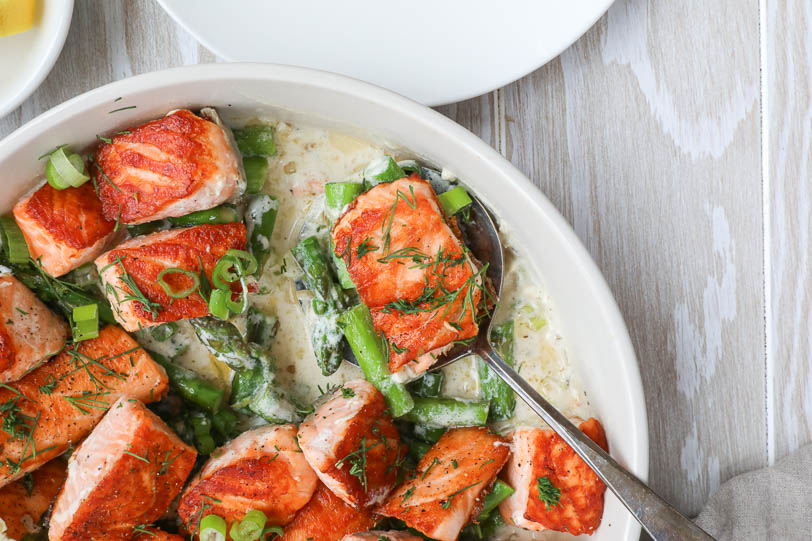 An image of spring salmon bites with asapargus in a white bowl with a spoon.