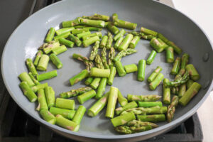 An image of asparagus sauteing in a pan.